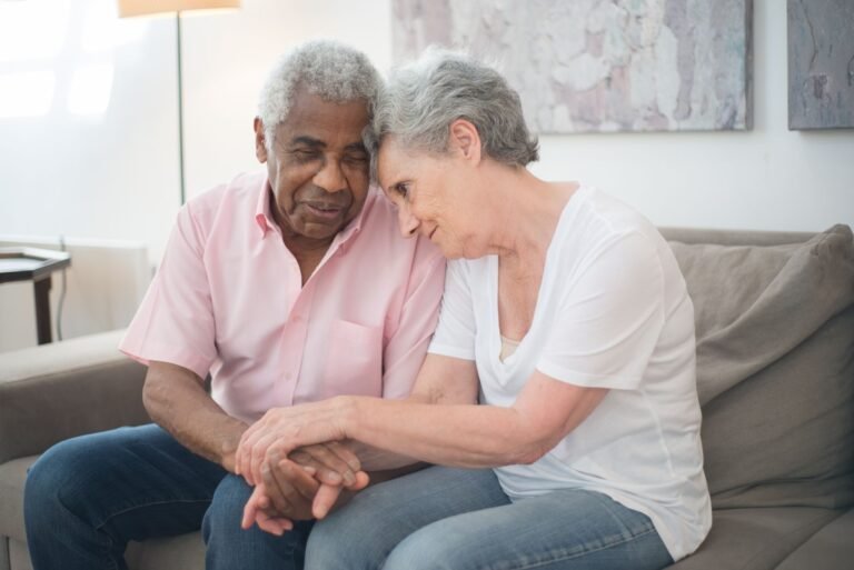 Respite care support: older couple holding hands at home while family support is arranged